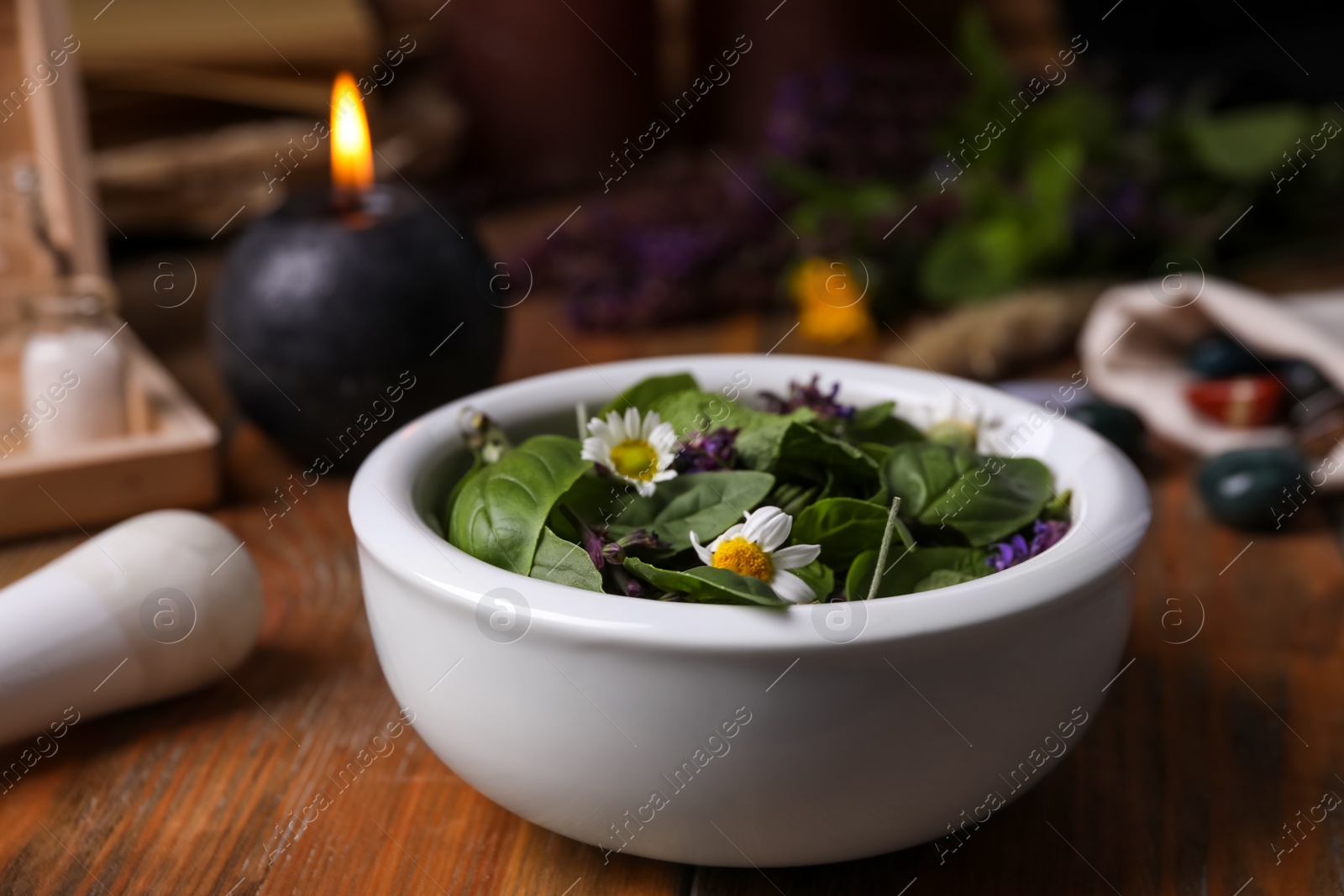 Photo of Composition with mortar, healing herbs and gemstones on wooden table, closeup