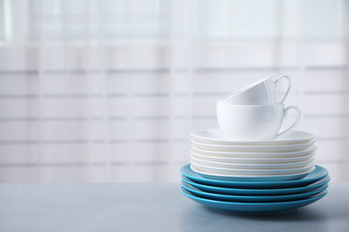 Photo of Set of clean tableware on light grey table. Space for text