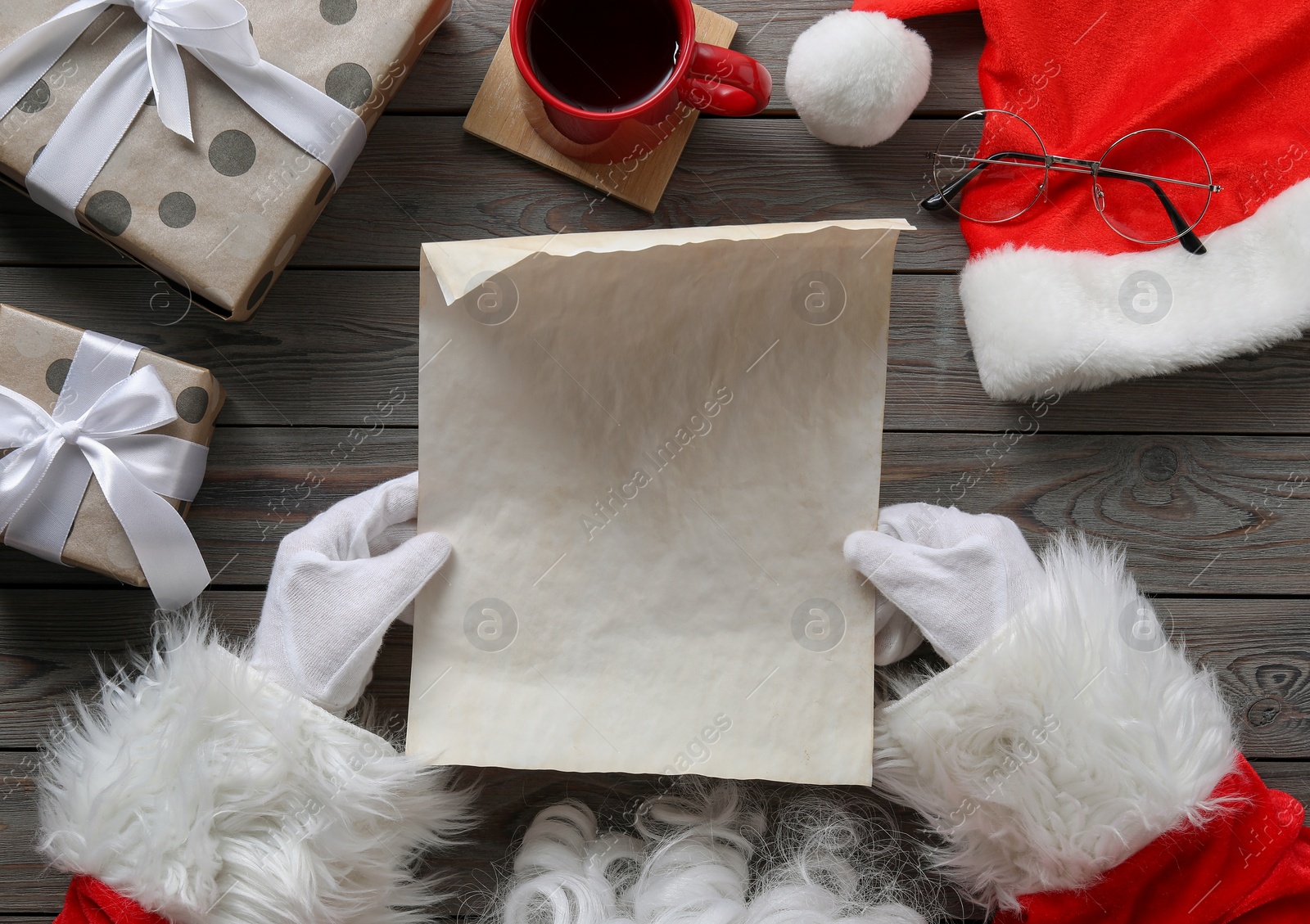 Photo of Santa Claus with letter, cup of drink and Christmas decor at wooden table, top view. Space for text