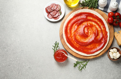 Photo of Flat lay composition with base and ingredients on light grey table, space for text. Pepperoni pizza recipe