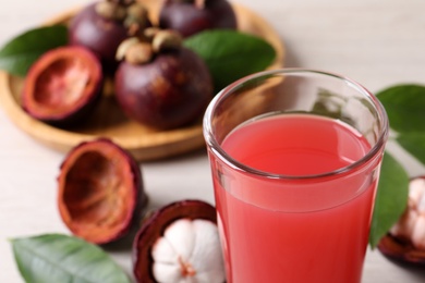 Delicious mangosteen juice in glass on table, closeup