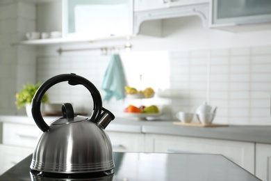 Modern kettle with whistle on stove in kitchen, space for text