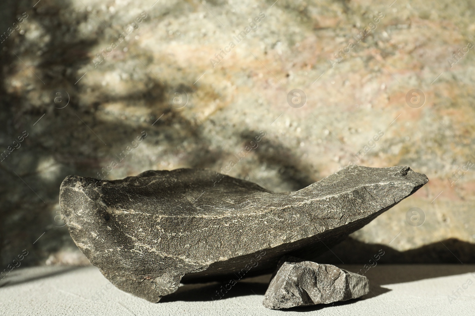 Photo of Presentation of product. Podium made of stones on light textured table. Space for text