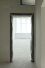 Door and window covered with plastic film in room