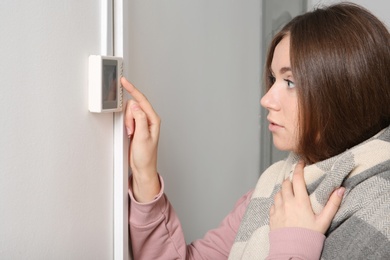 Photo of Woman adjusting thermostat on white wall. Heating system