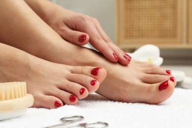 Photo of Woman with stylish red toenails after pedicure procedure on white terry towel, closeup