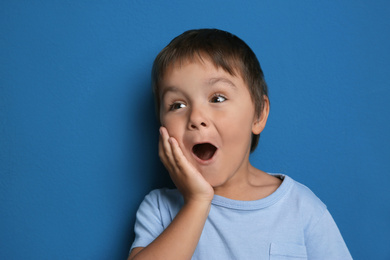 Photo of Portrait of surprised little boy on blue background