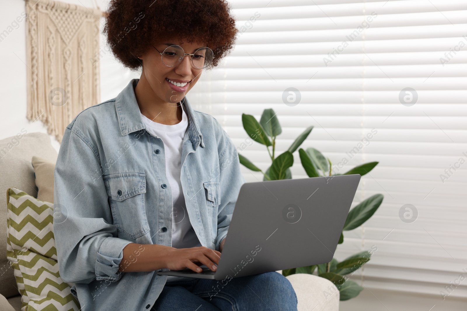 Photo of Young woman using modern laptop in room