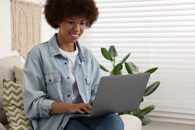 Photo of Young woman using modern laptop in room