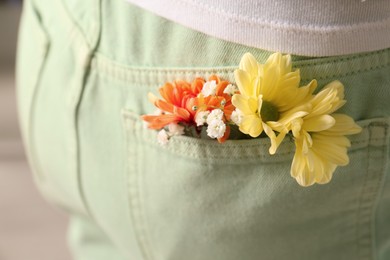 Photo of Woman with beautiful tender flowers in light green jeans pocket, closeup