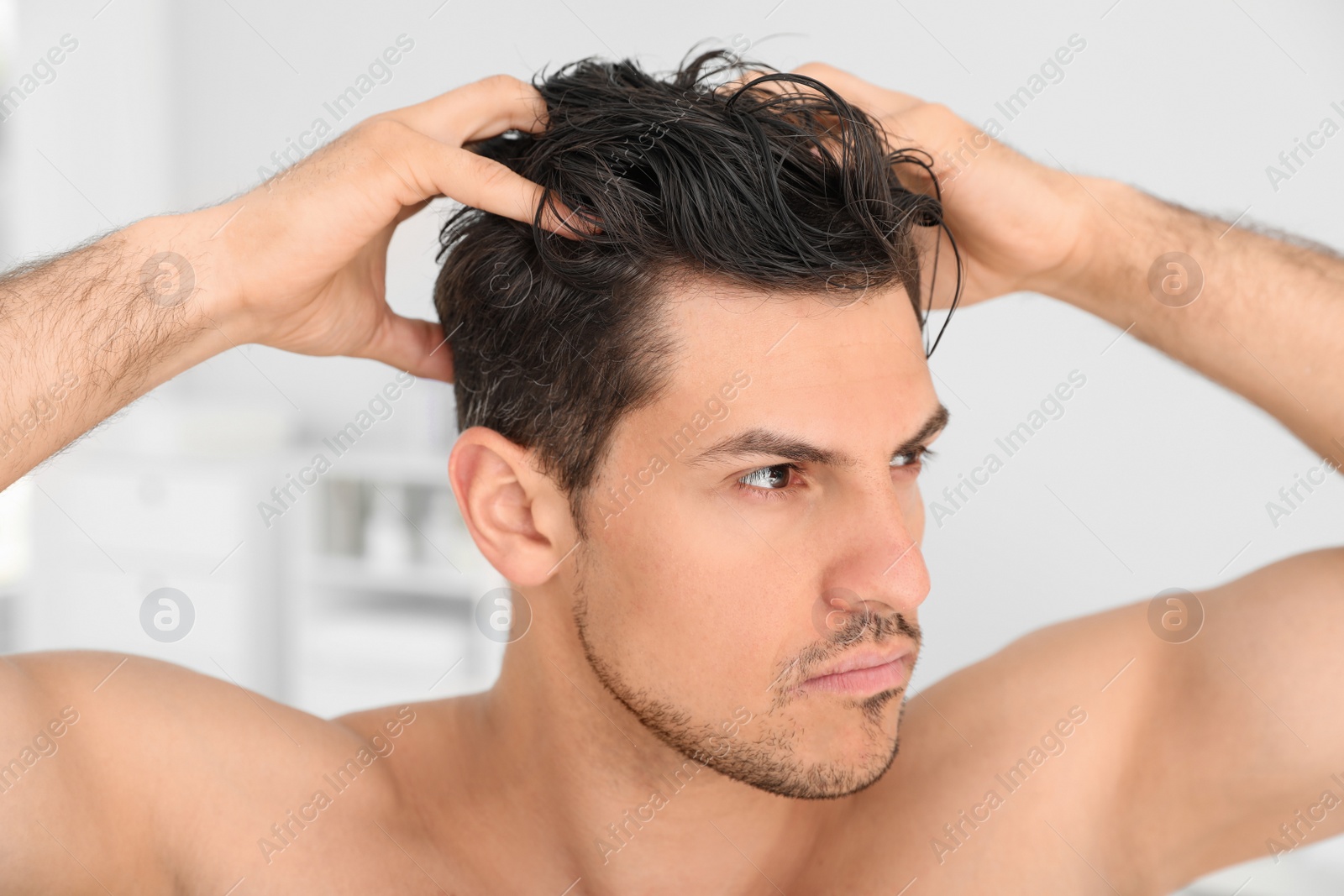 Photo of Handsome man applying hair conditioner in bathroom