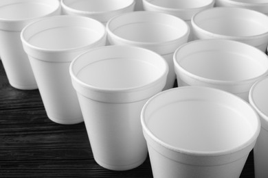 Photo of Many white styrofoam cups on black wooden table, closeup