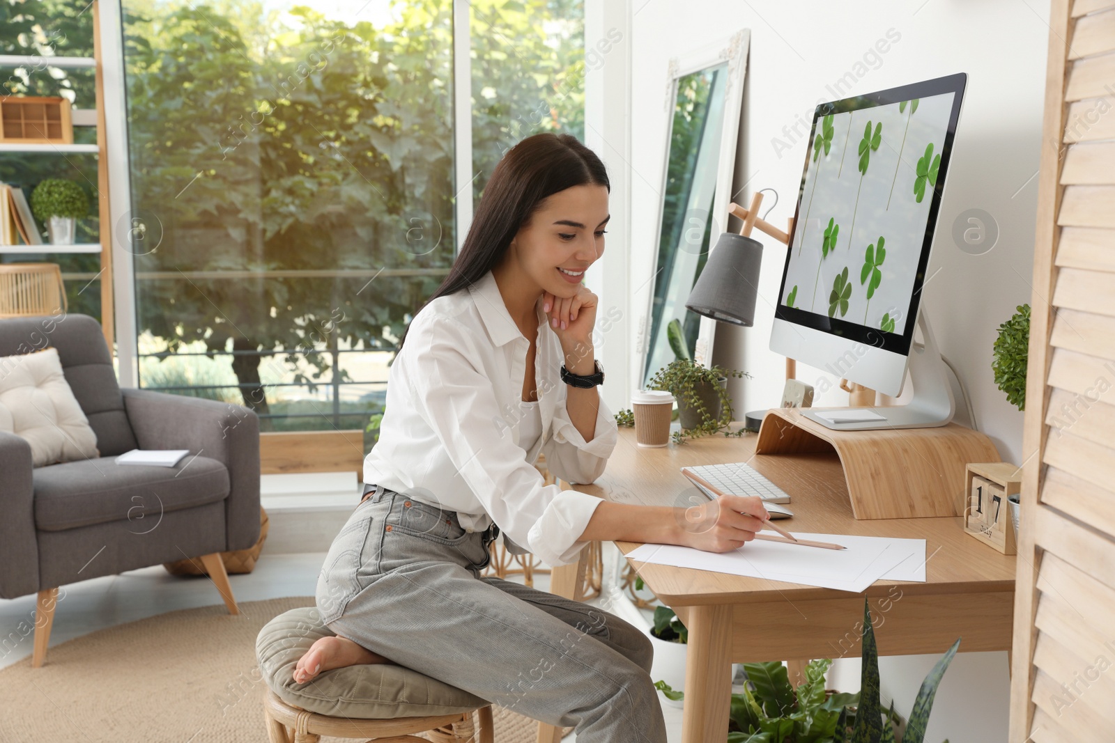 Photo of Young woman working at table in light room. Home office