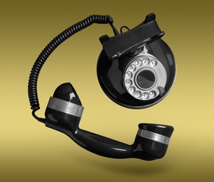 Image of Vintage black corded telephone flying in air on color background