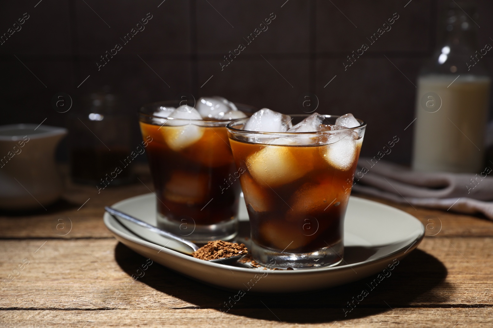 Photo of Refreshing iced coffee in glasses, ingredients and spoon on wooden table