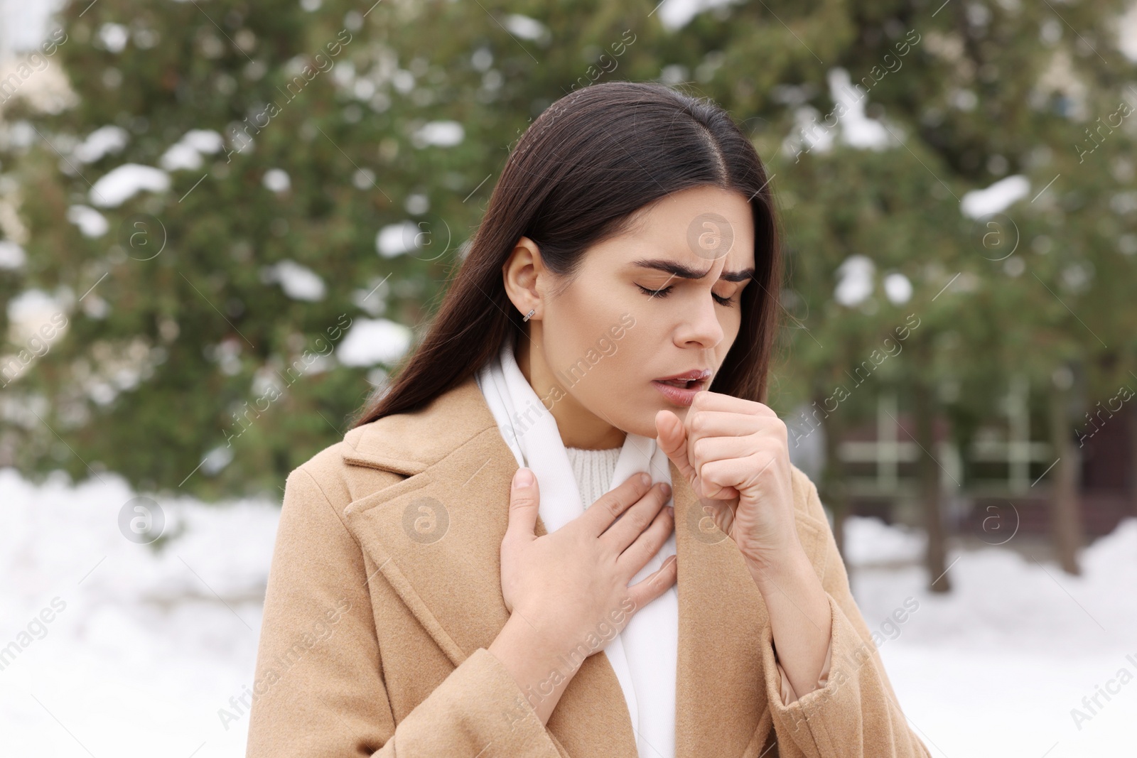 Photo of Woman in coat coughing outdoors. Cold symptoms