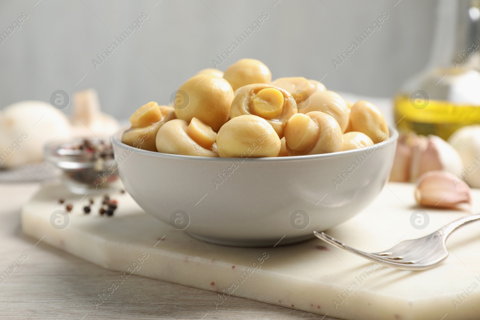 Photo of Tasty marinated mushrooms in bowl on wooden table, closeup