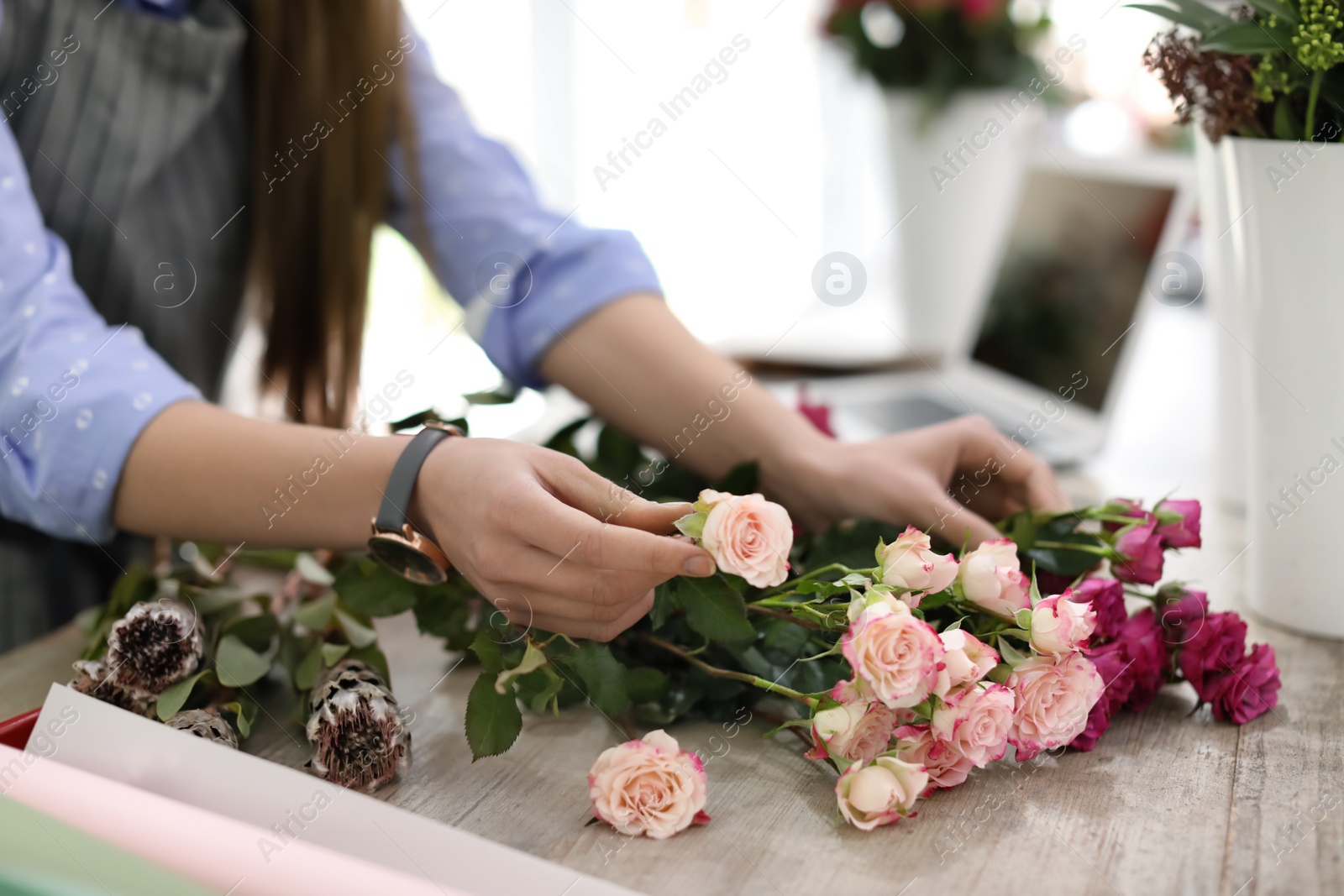 Photo of Female florist making beautiful bouquet in flower shop, closeup