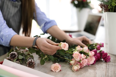 Female florist making beautiful bouquet in flower shop, closeup