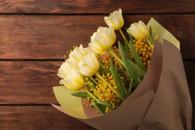 Bouquet with beautiful tulips and mimosa flowers on wooden table, top view. Space for text