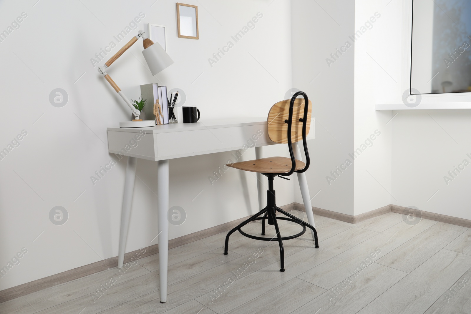 Photo of Comfortable workplace with white desk near wall at home