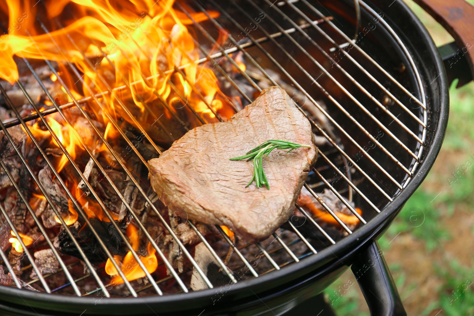 Photo of Tasty meat on barbecue grill with fire flames outdoors, closeup