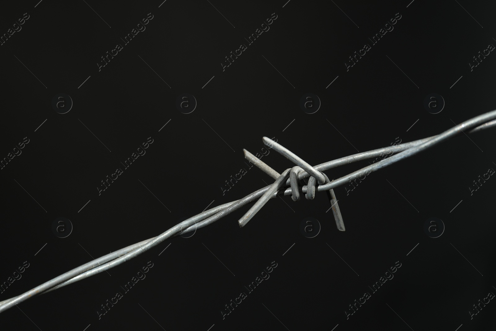 Photo of Shiny metal barbed wire on dark grey background, closeup