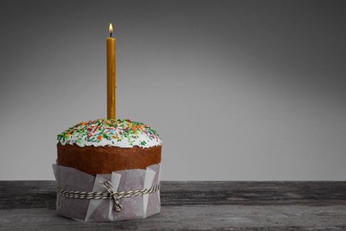 Photo of Traditional Easter cake with sprinkles and burning candle, space for text
