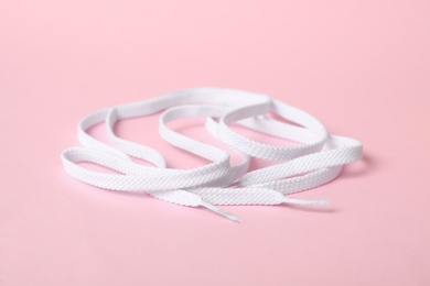 Photo of White shoe laces on light pink background