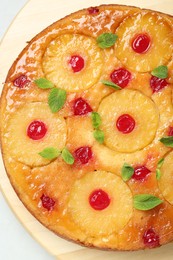 Tasty pineapple cake with cherries and mint on white table, top view