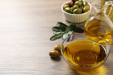 Photo of Fresh oil, ripe olives and green leaves on wooden table. Space for text