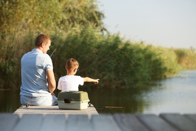 Dad and son fishing together on sunny day. Space for text
