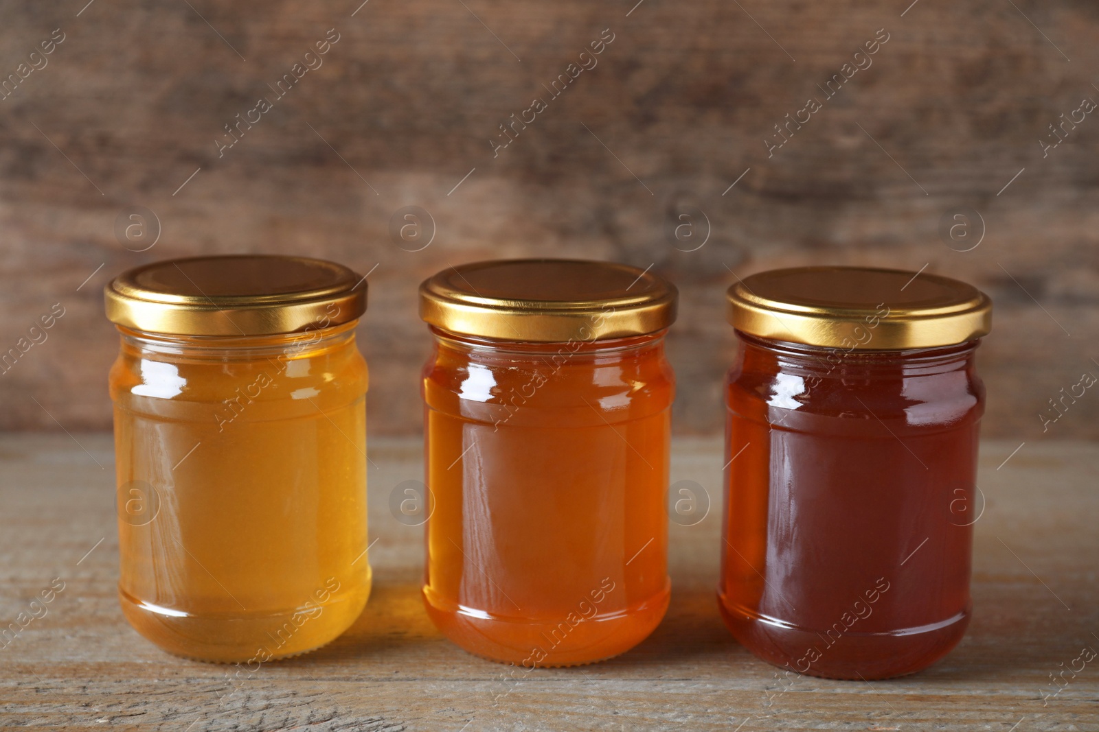 Photo of Jars with different types of organic honey on wooden table