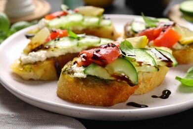 Delicious bruschettas with balsamic vinegar and toppings on table, closeup