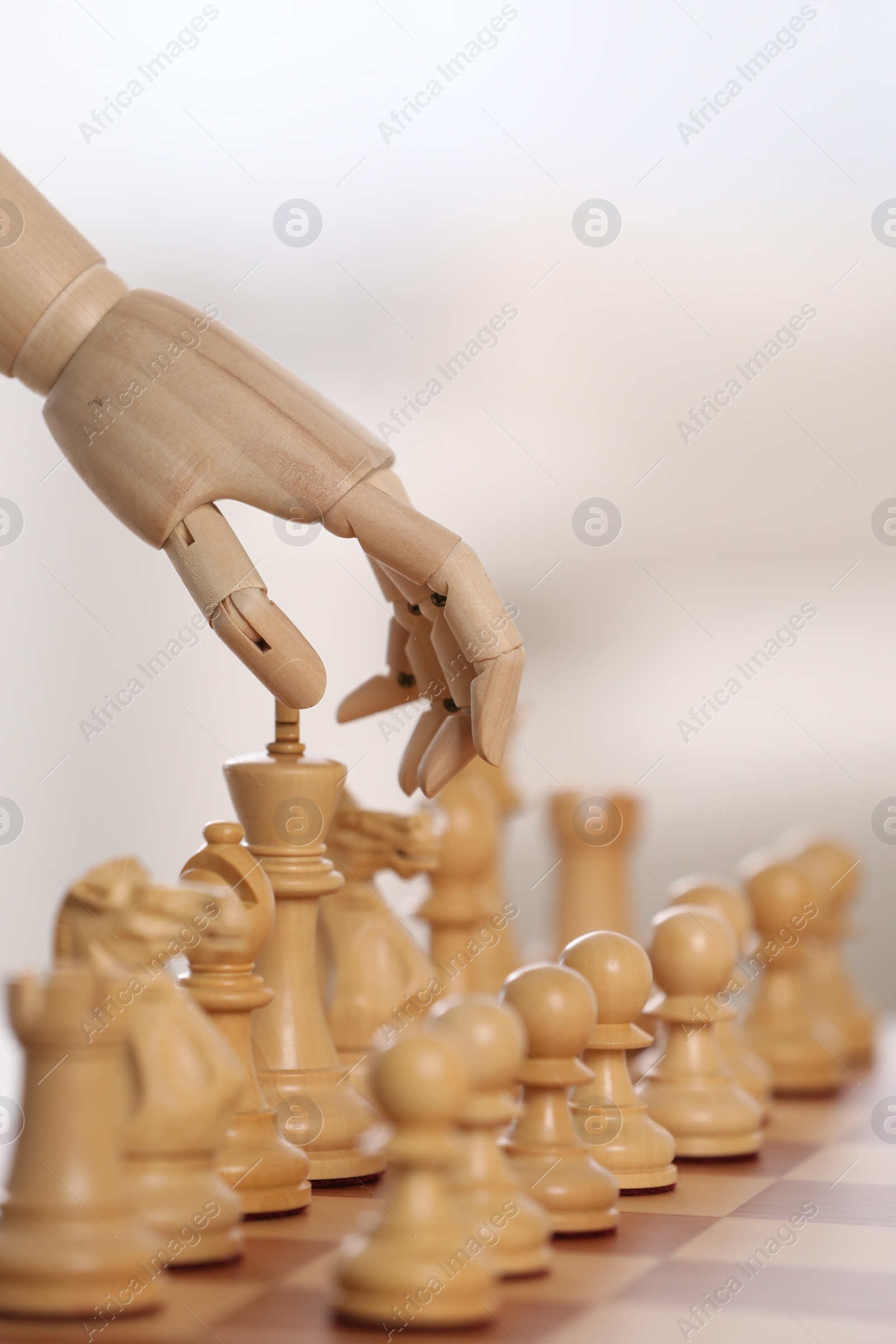 Photo of Robot moving chess piece on board against light background, closeup. Wooden hand representing artificial intelligence