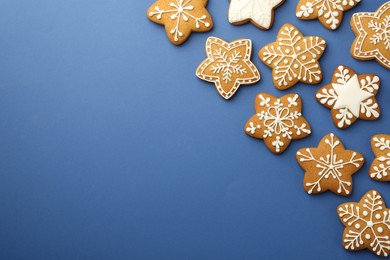 Photo of Tasty star shaped Christmas cookies with icing on blue background, flat lay. Space for text