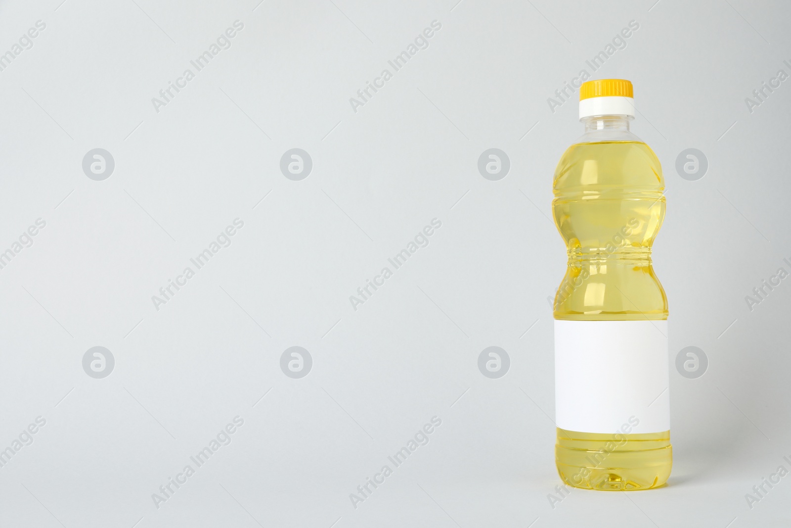 Photo of Bottle of cooking oil on light grey background. Space for text