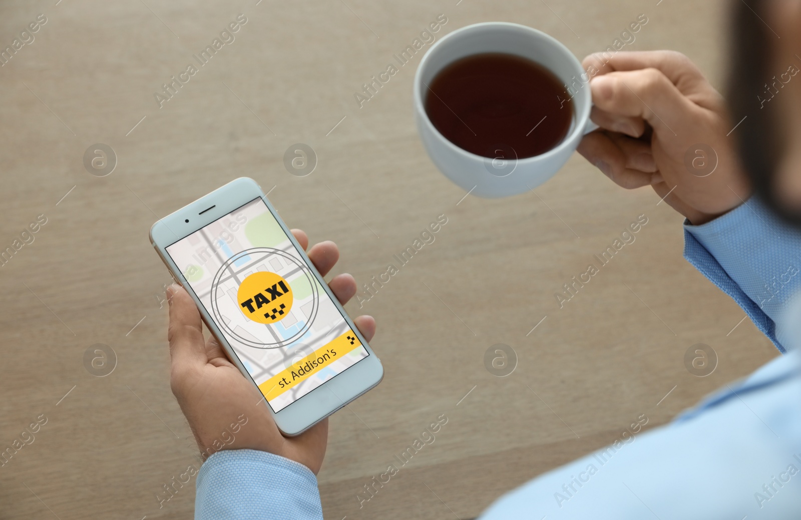 Photo of Man ordering taxi with smartphone at wooden table, closeup