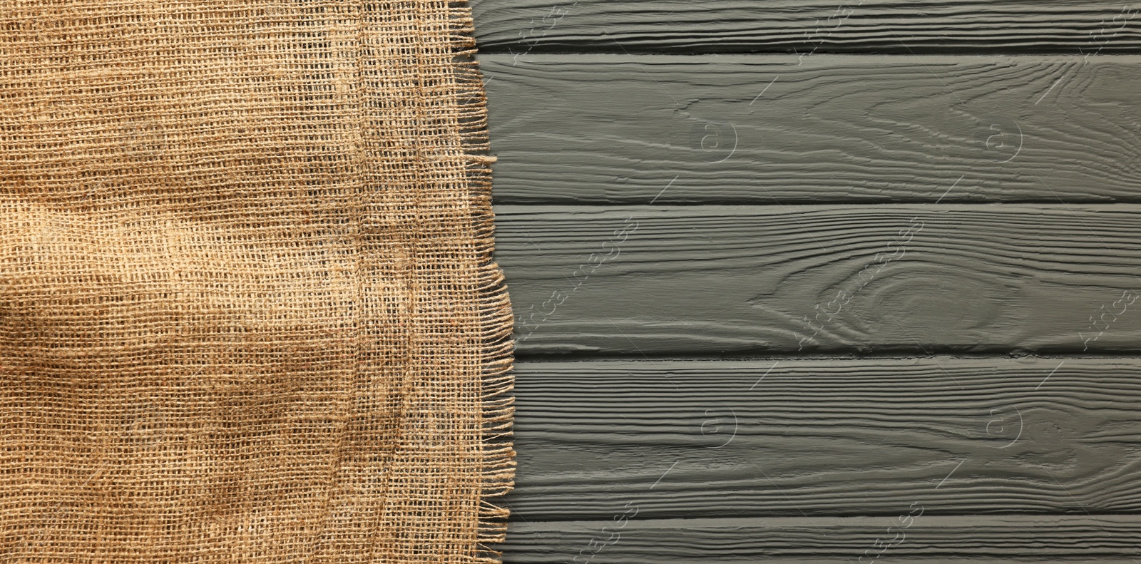 Photo of Burlap fabric on grey wooden table, top view. Space for text