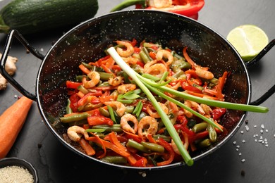 Shrimp stir fry with vegetables in wok and ingredients on black table