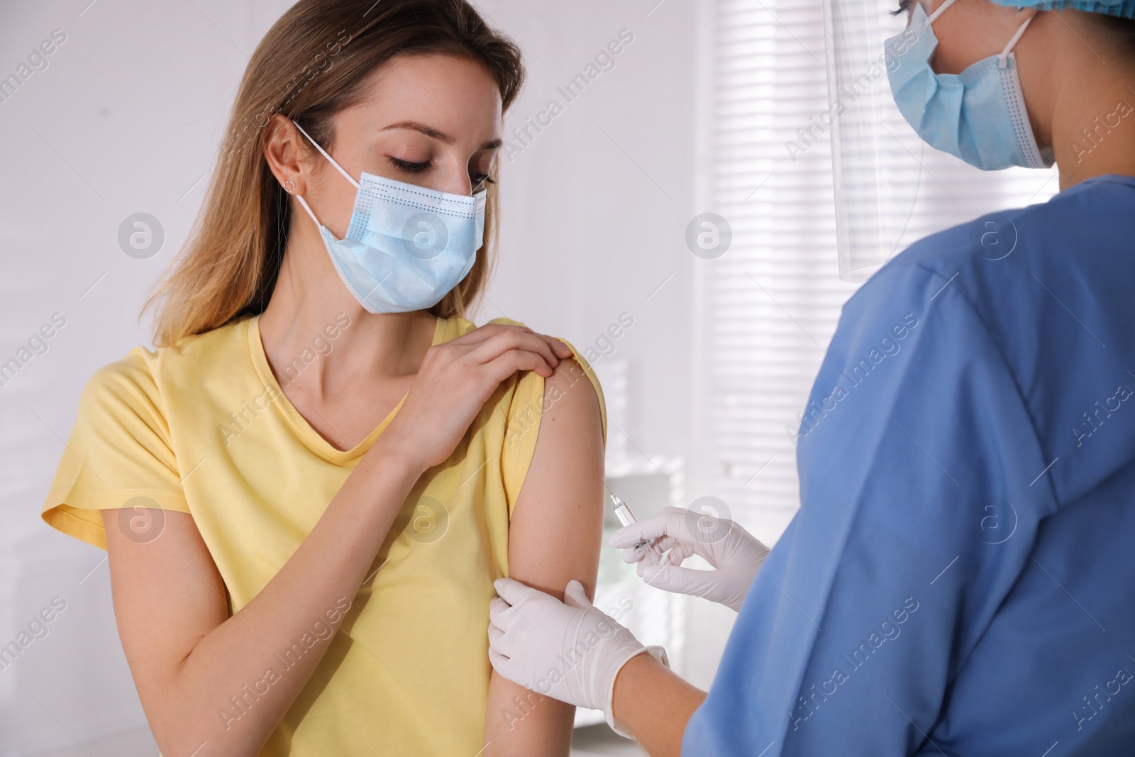 Photo of Doctor vaccinating young woman against Covid-19 in clinic