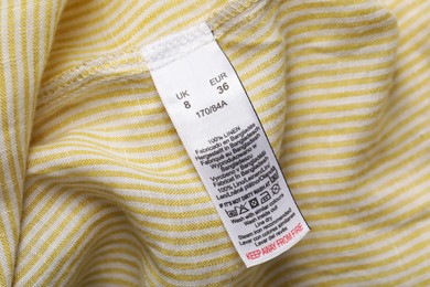 Photo of Clothing label with recommendations for care on striped garment, top view