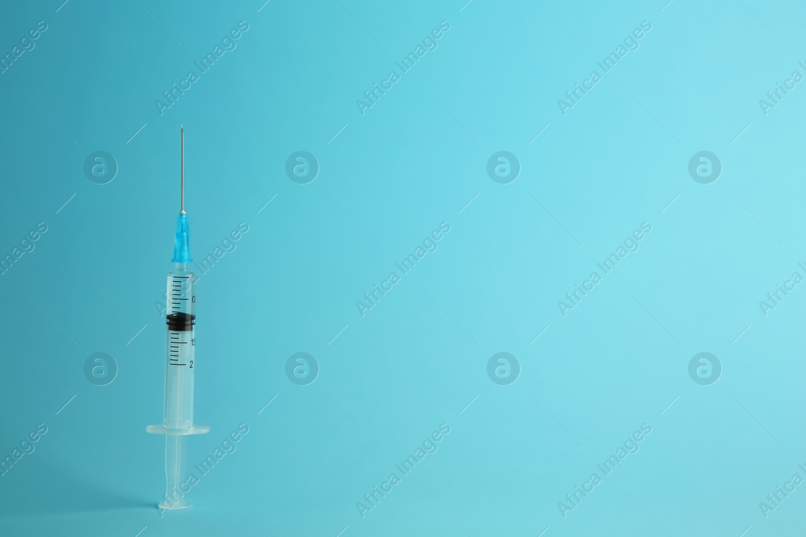 Photo of Medical syringe with liquid on light blue background, space for text