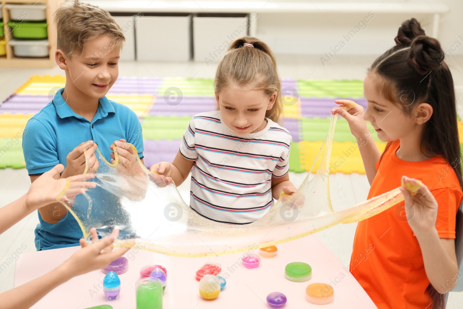 Photo of Happy children playing with slime at table indoors