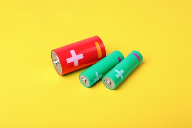 Photo of New AA and C batteries on yellow background