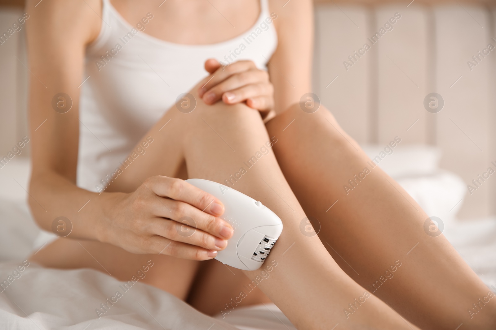 Photo of Woman doing leg epilation procedure on bed, closeup