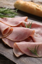 Photo of Slices of delicious ham and rosemary on table, closeup