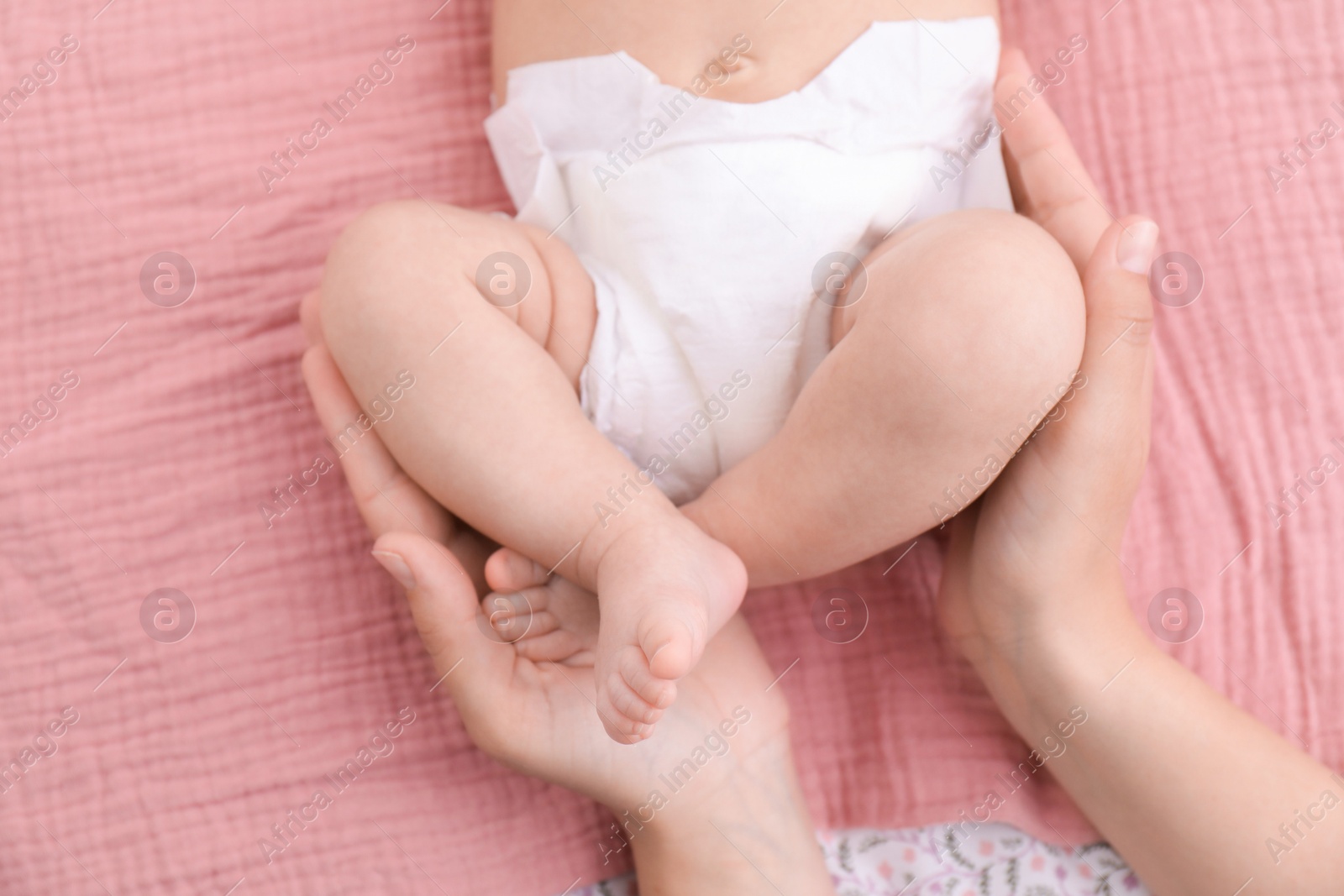 Photo of Mom with her baby in diaper on bed, closeup