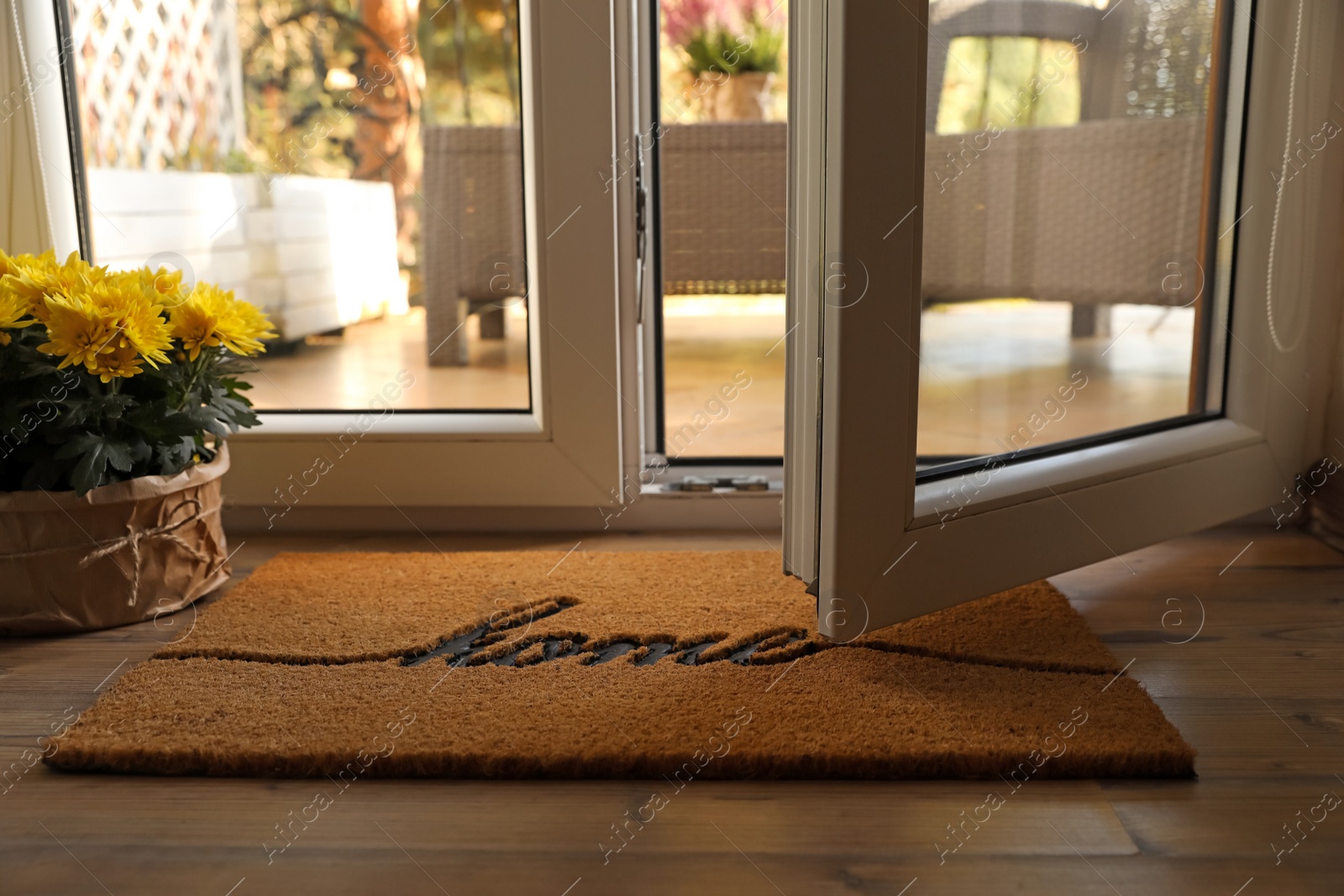 Photo of Doormat with word Home and flowers on parquet floor indoors