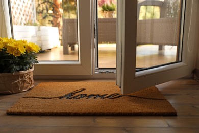 Photo of Doormat with word Home and flowers on parquet floor indoors